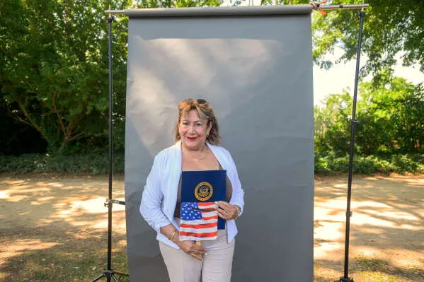 امرأة مبتسمة تحمل شهادة المواطنة الأمريكية وعلم الولايات المتحدة في احتفال منح الجنسية في Mount Vernon بفيرجينيا.