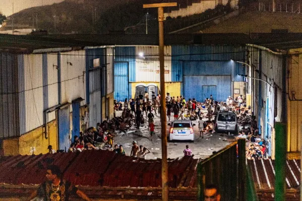 تجمّع كبير لمهاجرين في مركز استقبال بمدينة سبتة الإسبانية خلال أزمة الهجرة الجماعية من المغرب، مع تواجد أمني واضح في المشهد.