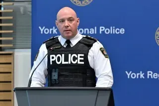 ضابط شرطة يتحدث في مؤتمر صحفي حول اعتقالات تتعلق بجريمة منظمة في تورنتو، مع التركيز على قضايا الرشوة والتآمر.