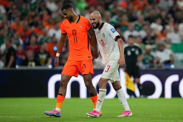 لاعبا هولندا والمغرب يسيران جنباً إلى جنب في مباراة كأس العالم 2030، يعكسان روح المنافسة والاحترام بين الفريقين.