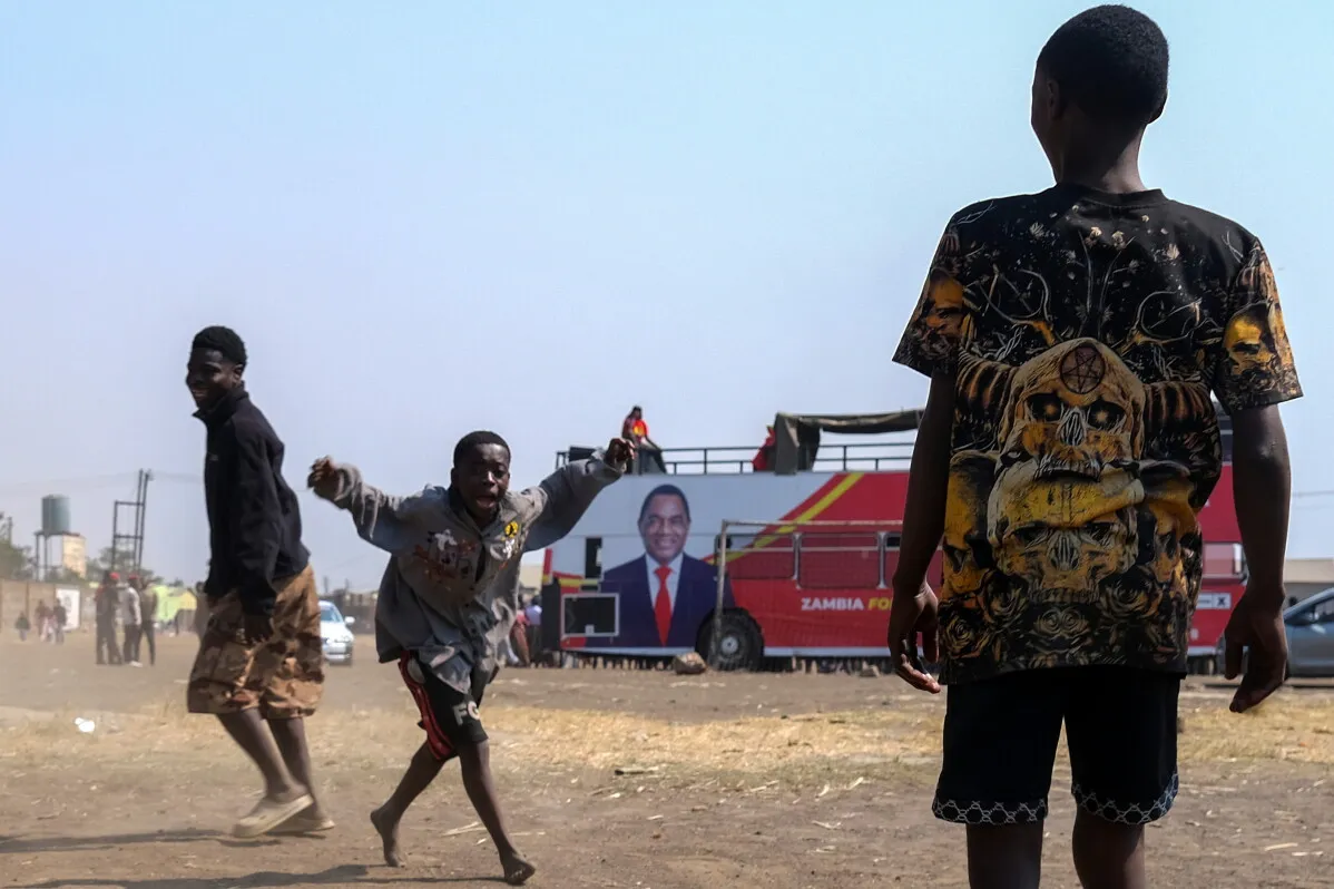 شبان يلعبون أمام حافلة انتخابية تحمل صورة الرئيس الزامبي Hakainde Hichilema خلال حملة الانتخابات الرئاسية في زامبيا.