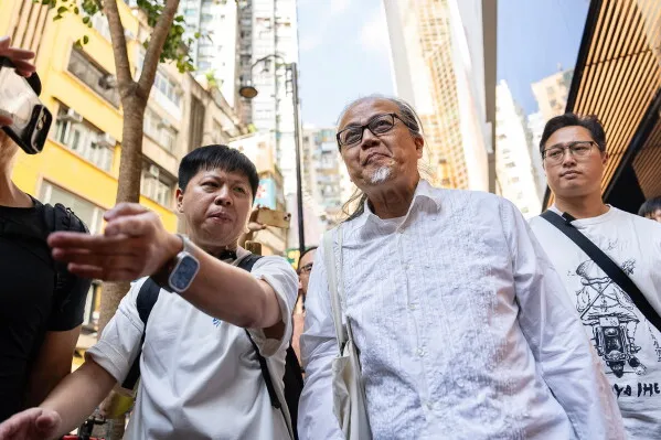 فنّان الأداء Sanmu Chen في حيّ Causeway Bay بهونغ كونغ، محاطًا بالناس، يعبر عن تعازيه لضحايا أحداث Tiananmen من خلال ربط خيطٍ أحمر بعمود.