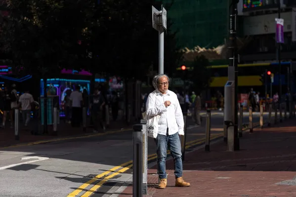 فنّان الأداء Sanmu Chen يقف في حيّ Causeway Bay بهونغ كونغ، محاولاً ربط خيطٍ أحمر بعمود للإشارات، تعبيراً عن تعازيه لضحايا أحداث Tiananmen.