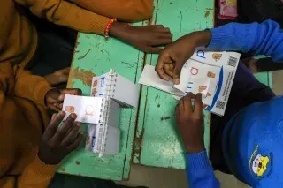 أيدي طلاب في مدرسة "جوهرة نادرة" بكينيا، يستخدمون أدوات تعليمية متعددة الحواس لتعزيز مهارات القراءة والكتابة.