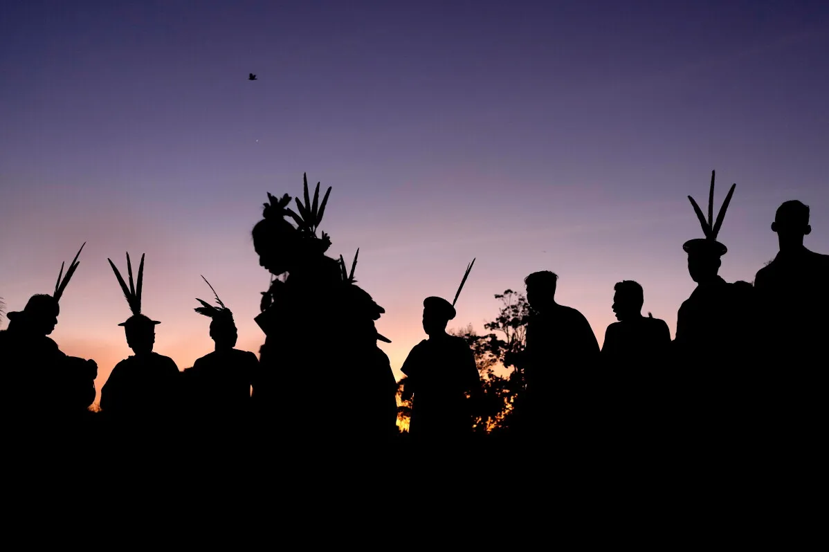 silhouettes لأعضاء مجتمع الأشانينكا الأصلي في الأمازون مع زخارف رأس تقليدية، تعبير عن مقاومتهم للحفاظ على أراضيهم من تهديدات تهريب المخدرات والعنف.