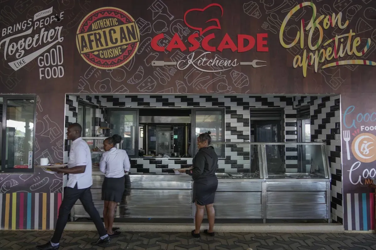 واجهة مطعم \"Cascade Kitchens\" في مدينة تاتو، حيث يظهر موظفون يقدمون خدمات الطعام في بيئة نظيفة ومنظمة، تعكس ثقافة الطعام الأفريقي.