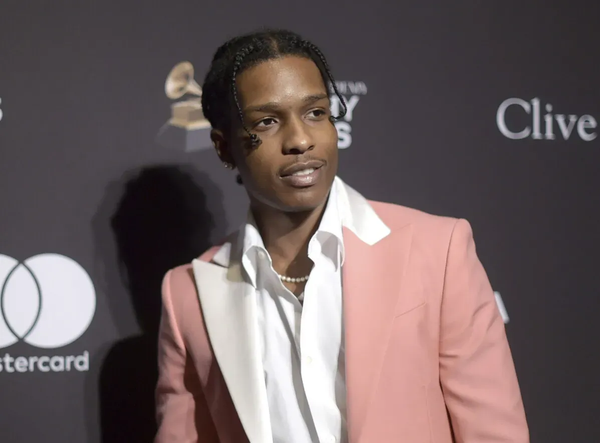 A$AP Rocky يظهر في حدث رسمي، يرتدي بدلة وردية أنيقة مع قميص أبيض، ما يعكس مكانته كفنان مشهور في عالم الموسيقى والأزياء.
