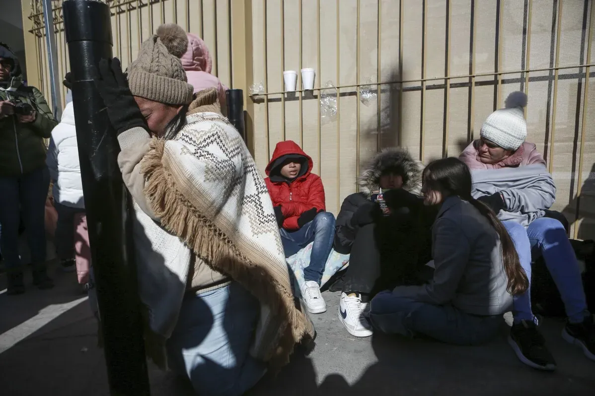 نساء وأطفال يجلسون معًا في الشارع قرب الحدود الأمريكية في تيخوانا، يتطلعون إلى مستقبلهم بعد إلغاء مواعيد الدخول.