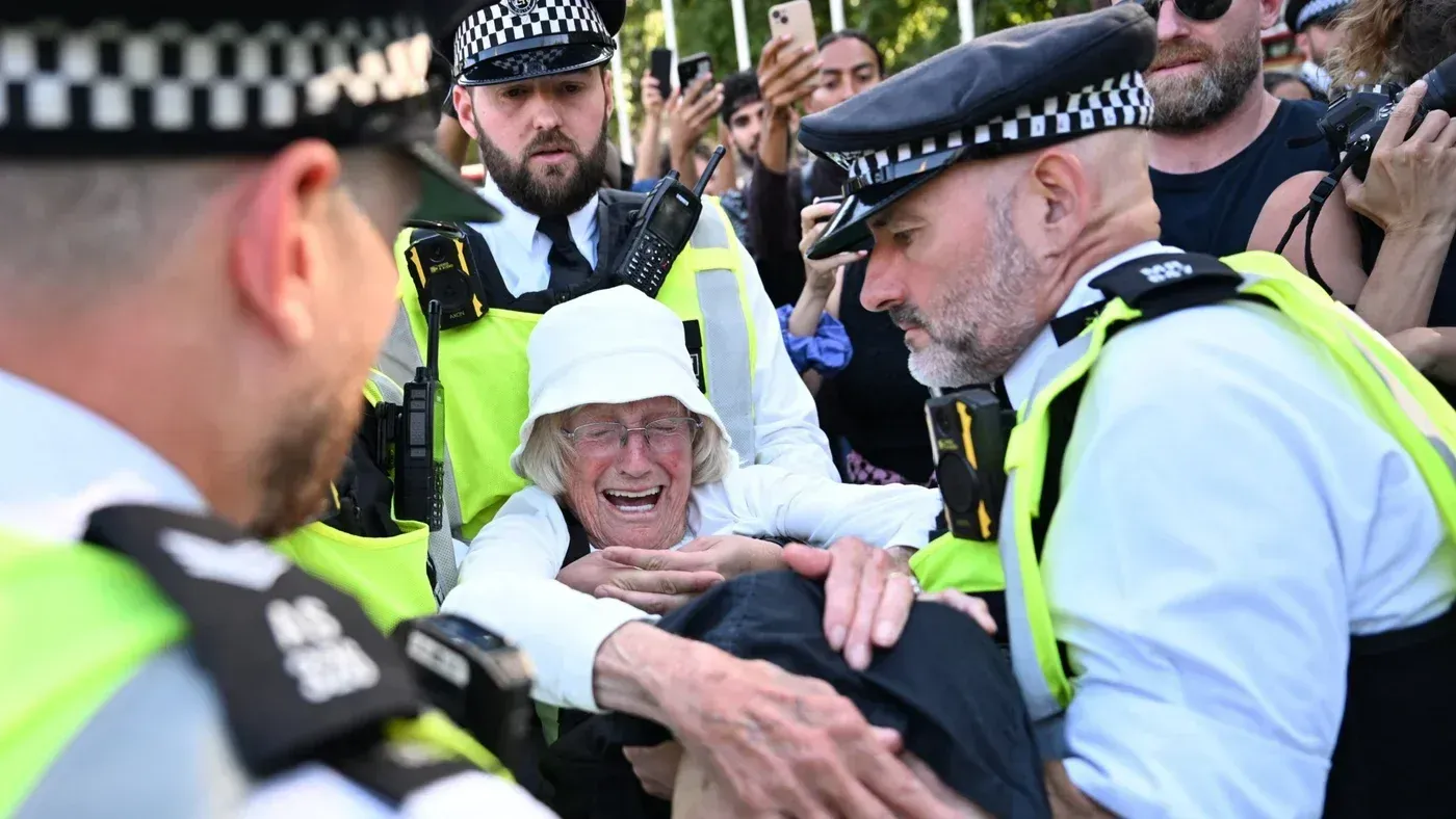 اعتقال ناشطة مسنّة خلال مظاهرة لدعم أسرى العمل الفلسطيني، مع وجود رجال شرطة يحاولون السيطرة على الوضع.