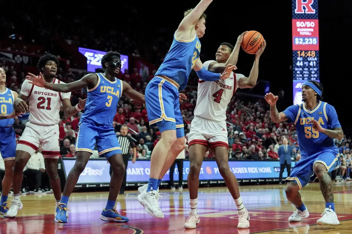 مباراة كرة سلة بين فريق روتجرز وفريق UCLA، حيث يظهر اللاعب إيس بيلي وهو يسدد الكرة وسط منافسة قوية من اللاعبين الآخرين.