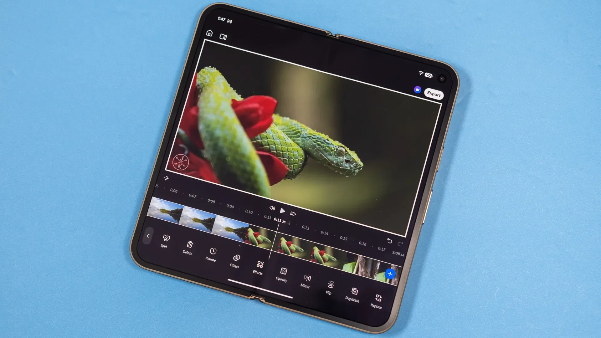 هاتف أندرويد قابل للطي يعرض واجهة تطبيق Adobe Premiere للمونتاج مع فيديو لثعبان على زهرة، يبرز أدوات تحرير الفيديو المجانية.