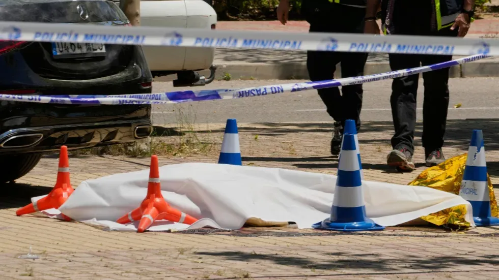 موقع الجريمة في مدريد حيث تم العثور على جسم أندري بورتنوف مغطى ببطانية بيضاء، مع وجود شرطة ومشاهدين في الخلفية.