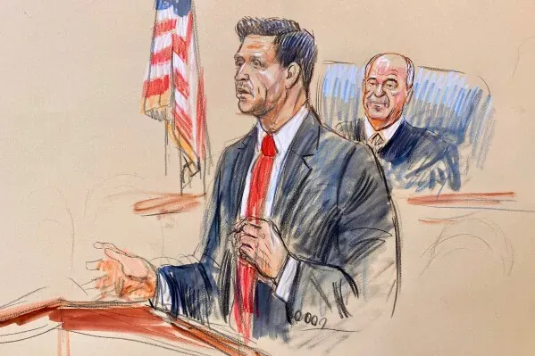 محامي يتحدث أمام هيئة المحلفين في محكمة فيرجينيا خلال محاكمة متهم بالتآمر في تفجير مطار كابول. الخلفية تظهر القاضي.