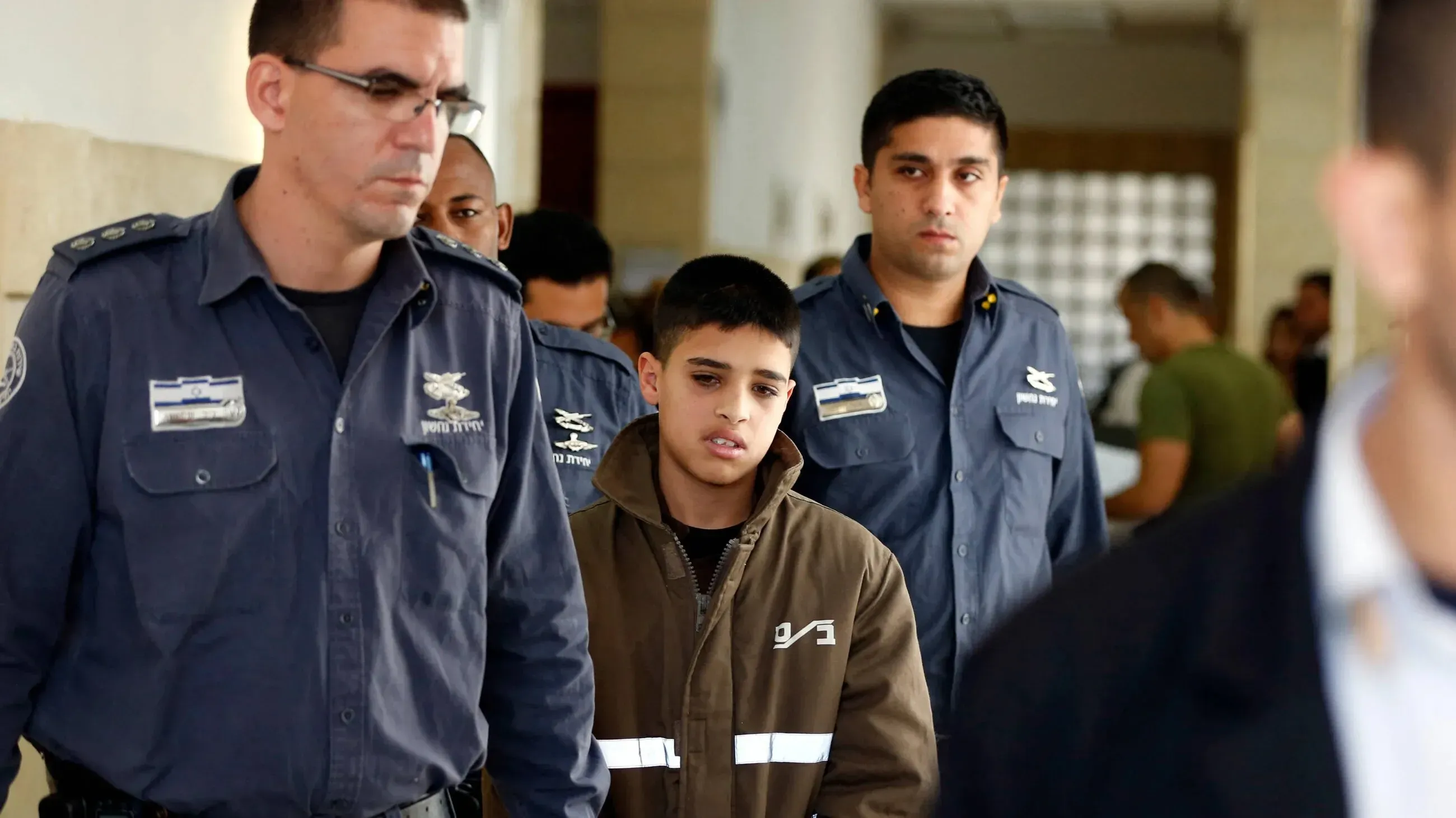 أحمد مناصرة، أسير فلسطيني، يُرافقه ضباط إسرائيليون في المحكمة، بعد اعتقاله بتهمة الشروع في القتل.