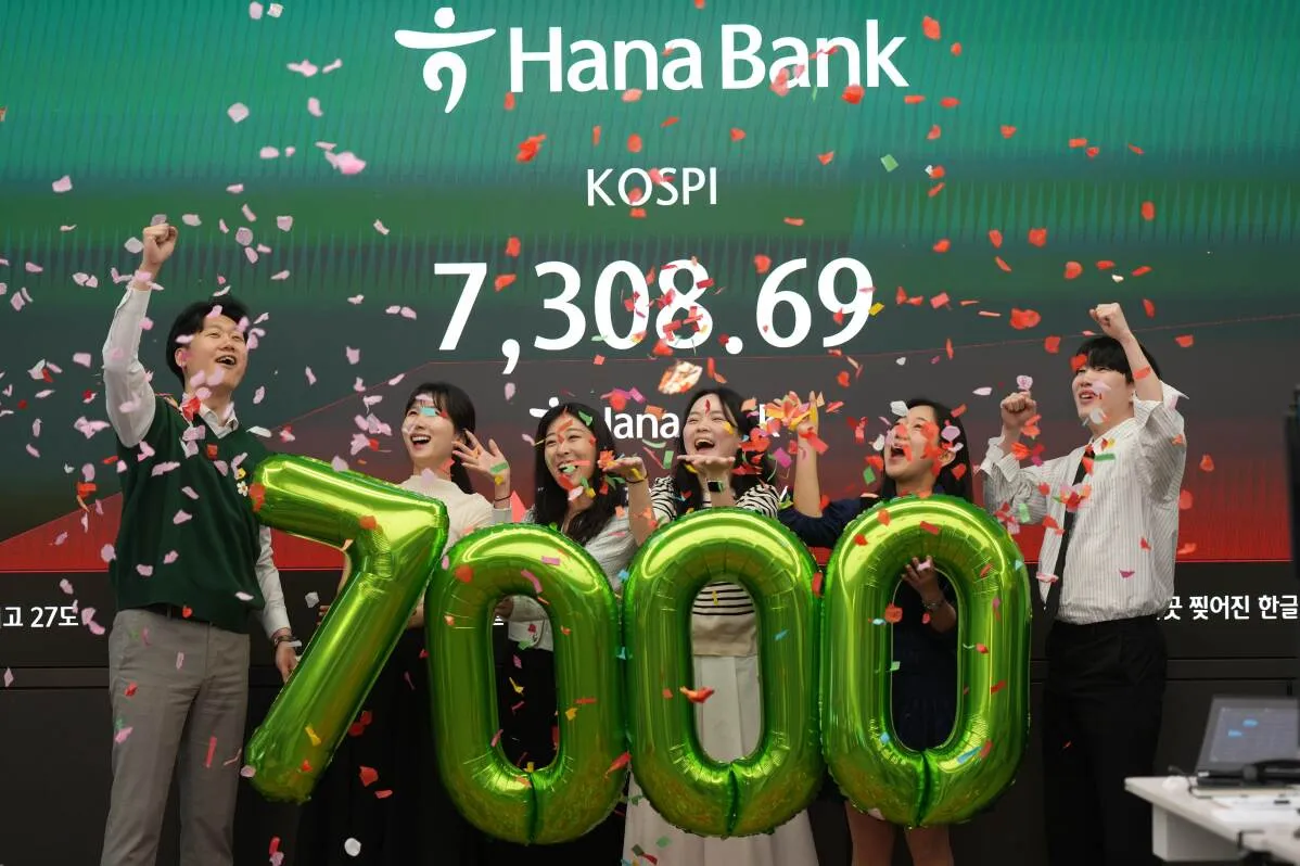 محتفلون في بورصة كوريا الجنوبية يرفعون بالونات تحمل الرقم 7000، مع عرض مؤشر Kospi الذي سجل 7308.69 نقطة.