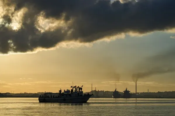 سفينة تحمل مساعدات إنسانية تقترب من رصيف هافانا، مع غيوم داكنة في السماء، تعكس الأزمة الاقتصادية والطاقة في كوبا.