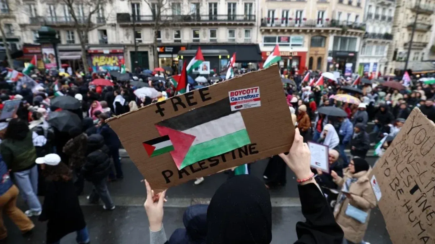 مظاهرة في باريس تطالب بتحرير فلسطين، حيث يحمل المتظاهرون لافتات تعبر عن دعمهم للقضية الفلسطينية وسط أجواء احتجاجية.