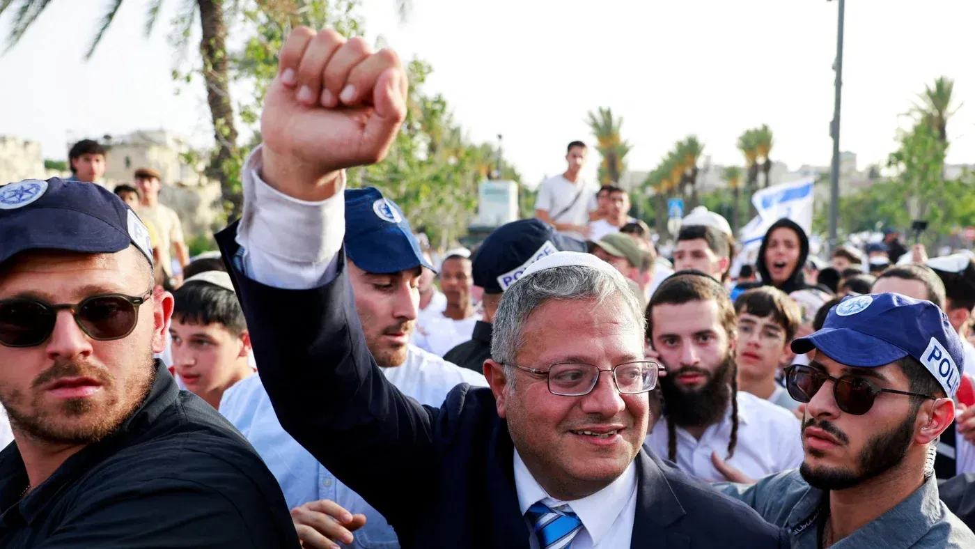 وزير الأمن القومي الإسرائيلي إيتمار بن غفير يرفع يده خلال تجمع حاشد، محاطًا بمؤيدين وعناصر أمن، في سياق تصاعد التوترات في المنطقة.