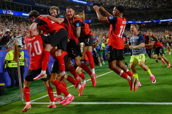لاعبو منتخب سويسرا يحتفلون بحماس بعد هدف في مباراة كأس العالم، مع التركيز على روح الفريق والتنافس الدولي.