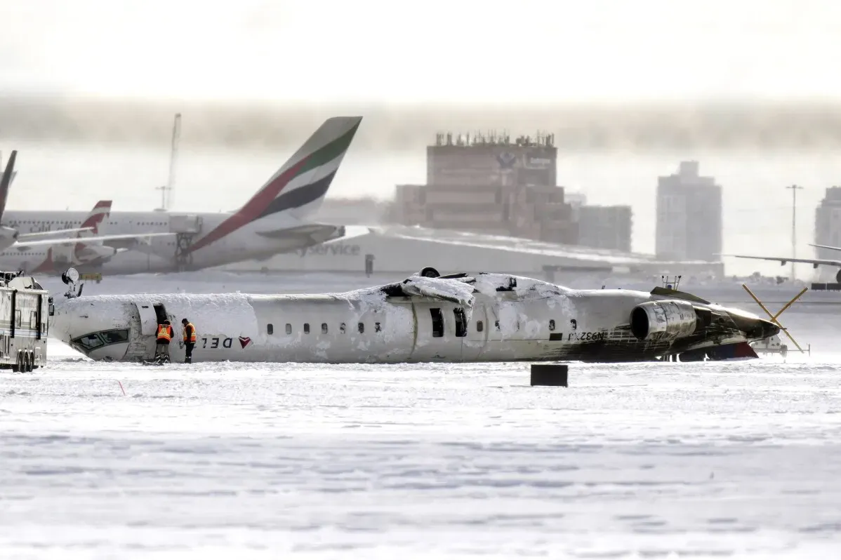 تحطمت طائرة دلتا الجوية من طراز CRJ-900 على مدرج مطار بيرسون في تورنتو، مقلوبة ومغطاة بالثلوج، مع وجود طاقم الطوارئ في الموقع.