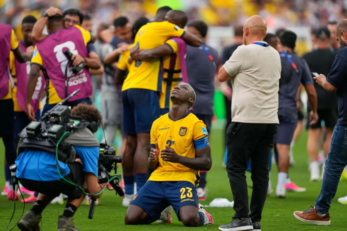 لاعب إكوادوري يرتدي زي الفريق الأصفر يركع على أرض الملعب مع فريقه في خلفية الصورة خلال مباراة كأس العالم في مكسيكو سيتي.
