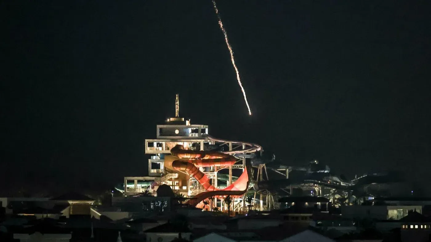 صورة تظهر مركز بيانات مضاء في الليل مع قذيفة تنطلق في السماء، في سياق حريق أدى إلى تعطل خدمات أمازون السحابية في الإمارات.