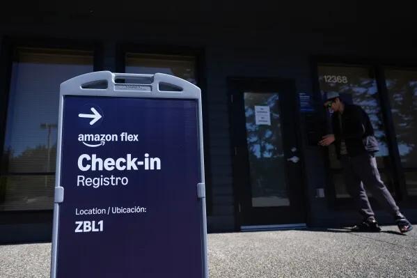 لافتة تشير إلى نقطة تسجيل دخول خدمة Amazon Flex، مع شخص يقترب من الباب، تعكس جهود Amazon في تحسين خدمات التوصيل السريع.