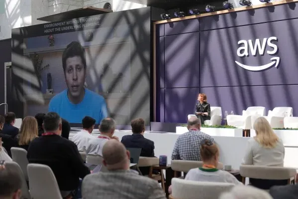 تظهر الصورة Sam Altman، الرئيس التنفيذي لـOpenAI، يتحدث عبر فيديو مسجل خلال فعالية Amazon، مع شعار AWS خلفه.