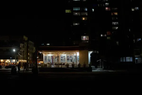 تظهر الصورة مقهى مغلق في هافانا ليلاً، محاطاً بمباني سكنية مظلمة، مما يعكس تراجع الحياة الليلية بسبب الأزمات الاقتصادية.