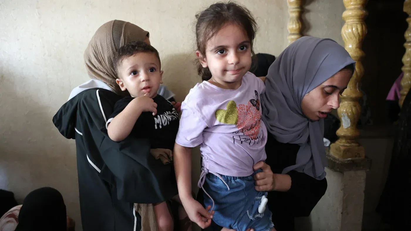 نساء يحملن أطفالًا في مخيم للنازحين بغزة، يعبرن عن الأمل والحنان وسط الظروف الصعبة التي يواجهها السكان.