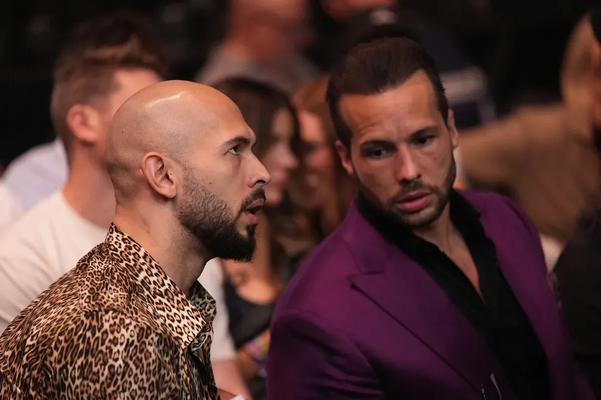 أندرو تيت وتريستان تيت يجلسان معاً في قاعة تي موبايل أرينا خلال حدث UFC 313، مع مشاعر التوتر والترقب في الأجواء.