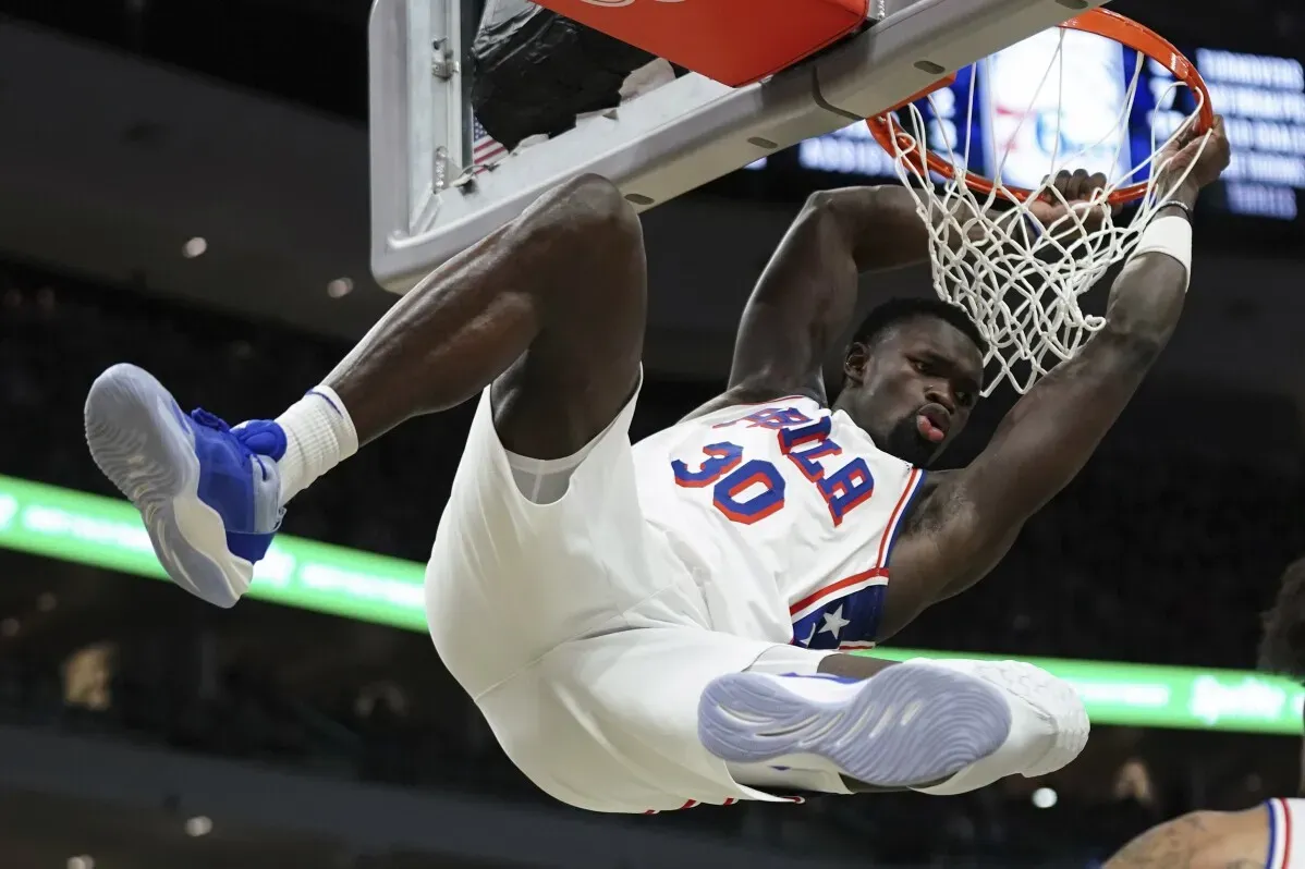 أدين بونا، لاعب فريق فيلادلفيا 76ers، يسجل نقطة خلال المباراة، معلقاً في السلة، وسط أجواء حماسية.