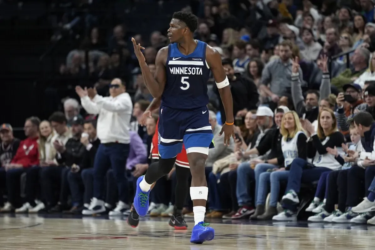 أنتوني إدواردز، لاعب مينيسوتا تمبروولفز، يحتفل بعد تسجيل نقطة في مباراة كرة سلة، مع جمهور متفاعل في الخلفية.