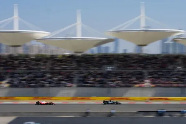 سباق سيارات الفورمولا 1 يظهر سيارة مرسيدس تتنافس مع سيارة فيراري، وسط حشد جماهيري كبير وأبنية حديثة في الخلفية.