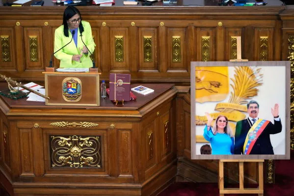 تظهر Delcy Rodríguez، الرئيسة الفنزويلية بالإنابة، أثناء إلقاء كلمة في الجمعية الوطنية، مع صورة لنیکولاس مادورو خلفها، مما يعكس التوترات السياسية في فنزويلا.