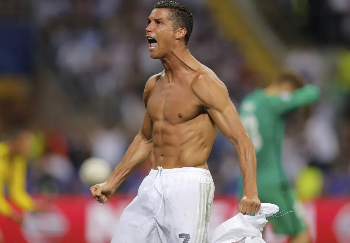 كريستيانو رونالدو يحتفل بعد تسجيل هدف، عارٍ من الجزء العلوي، يعبر عن حماسه. يُعتبر أحد أعظم هدافي كرة القدم عبر التاريخ.