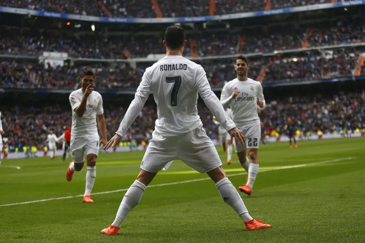 كريستيانو رونالدو يحتفل بتسجيل هدف مع ريال مدريد، محاطاً بزملائه في الملعب، وسط حماس الجماهير.