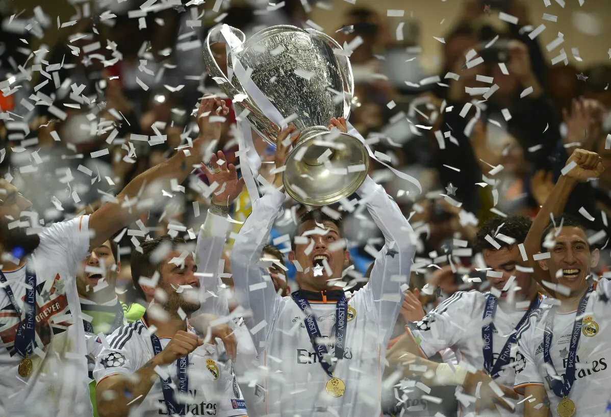 رونالدو يحتفل بفوز ريال مدريد بلقب دوري أبطال أوروبا، رافعًا الكأس وسط الأعلام والألعاب النارية، مع زملائه في الفريق.