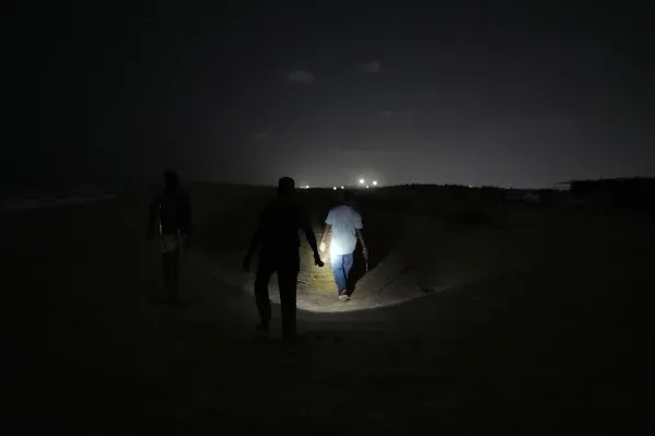 متطوعون يسيرون على شاطئ مظلم في تشيناي ليلاً، يحمل أحدهم مصباحاً للبحث عن أعشاش السلاحف البحرية وحمايتها.