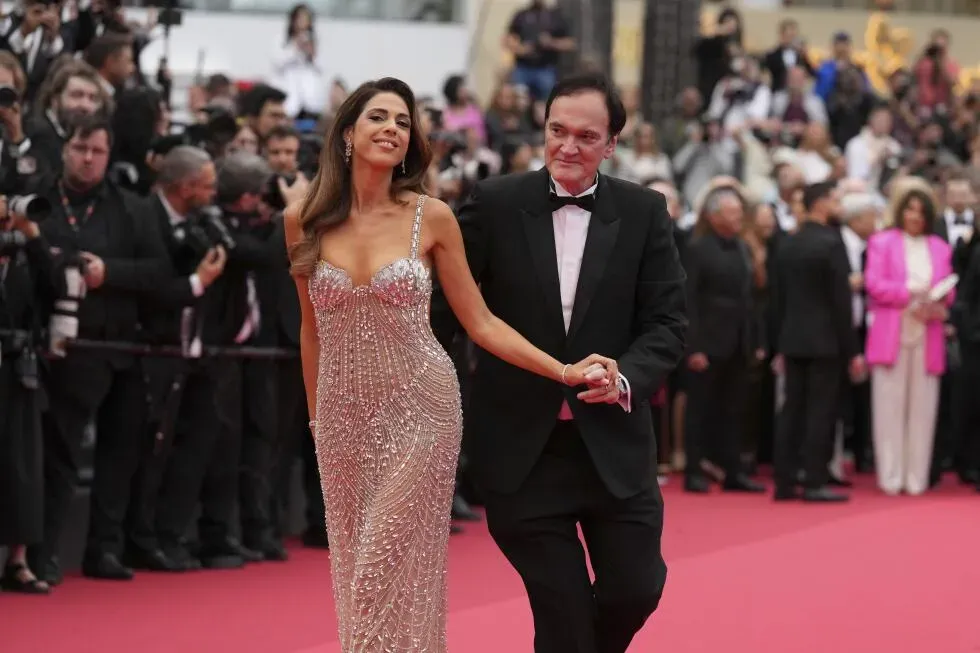 مهرجان كان السينمائي يشهد ظهور شخصية معروفة بفستان لامع، بينما تم التقاطها مع شريكها على السجادة الحمراء وسط حشود من المصورين.