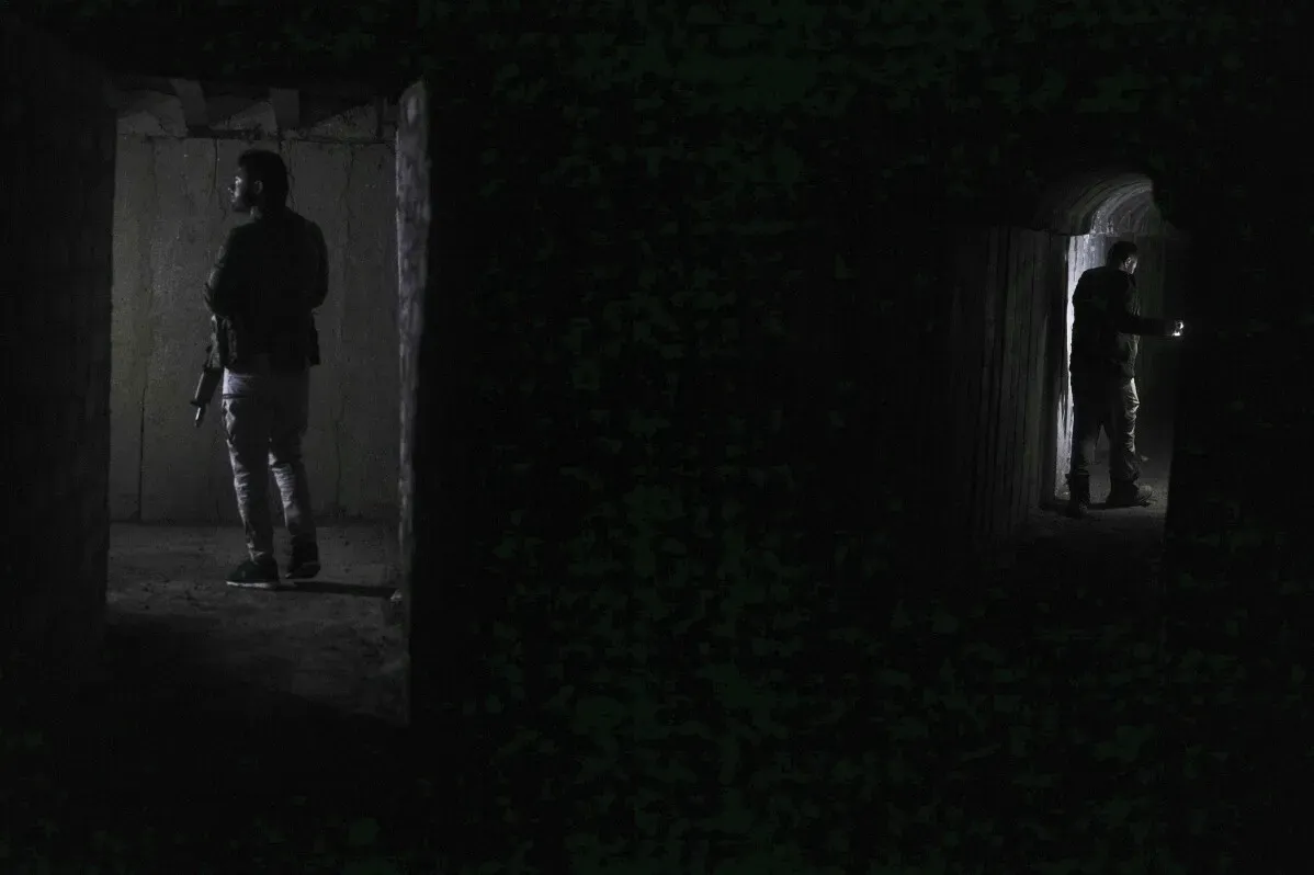 شخص يحمل سلاحًا داخل نفق مظلم في تل رفعت، سوريا، حيث تُظهر الصورة آثار الحرب والتحديات التي تواجه السكان العائدين.