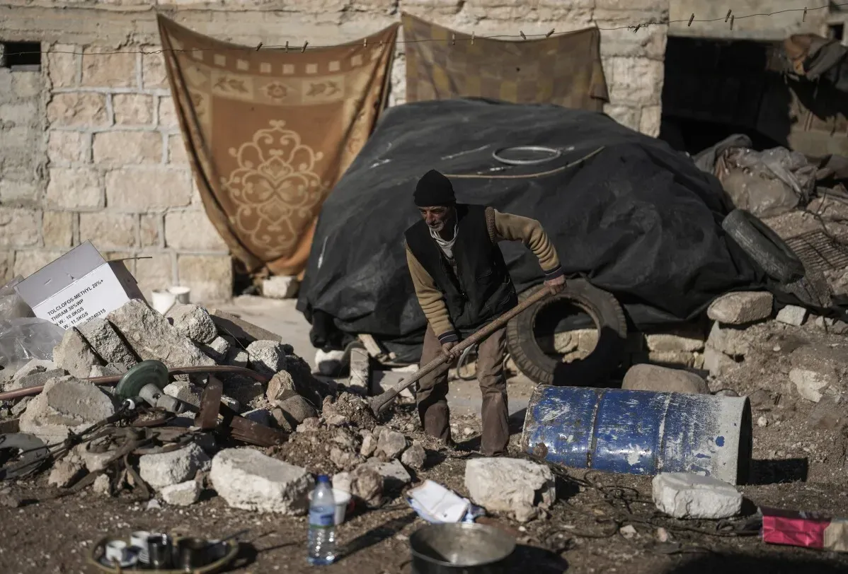 رجل مسن يعمل على إزالة الأنقاض في تل رفعت بسوريا، حيث تظهر آثار الحرب وركام المنازل المدمرة حوله.