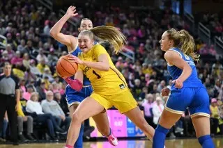 أوليفيا مايلز، لاعبة كرة سلة من جامعة تي سي يو، تتنافس على الكرة وسط لاعبتين من الفريق المنافس، في مباراة حماسية.