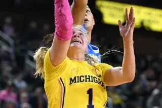 لاعبة كرة السلة أوليفيا أولسون من جامعة ميشيغان تسجل نقطة خلال مباراة، مرتدية زي الفريق الأصفر، مع التركيز على الأداء المتميز في الأسبوع 15.