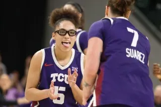 أوليفيا مايلز، لاعبة كرة سلة من جامعة تي سي يو، تحتفل مع زميلتها بعد تسجيل نقاط في مباراة، مرتدية نظارات.