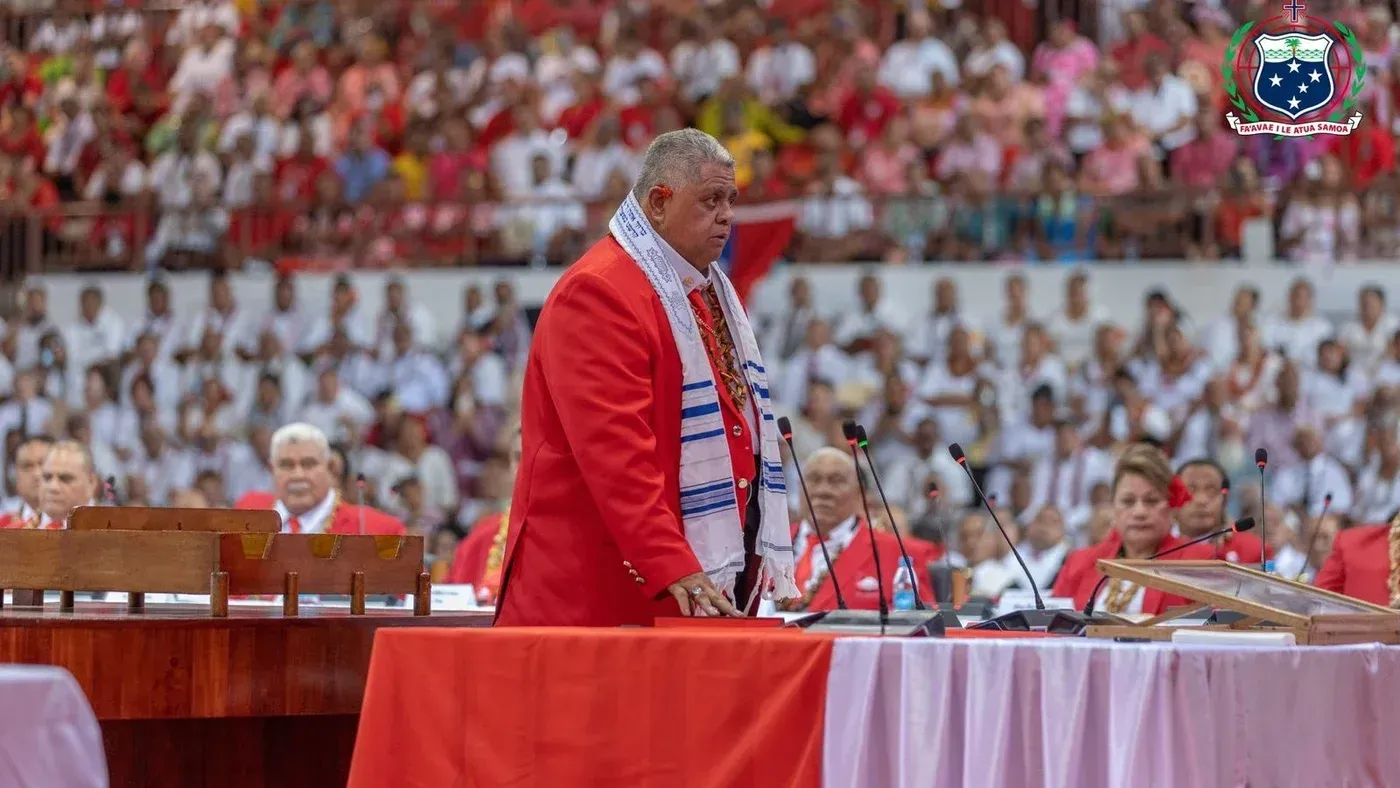 رئيس وزراء ساموا، لاولي ليواتيا شميت، يرتدي زيًا رسميًا أثناء إعلان افتتاح سفارة ساموا في القدس، وسط حشد من الحضور.