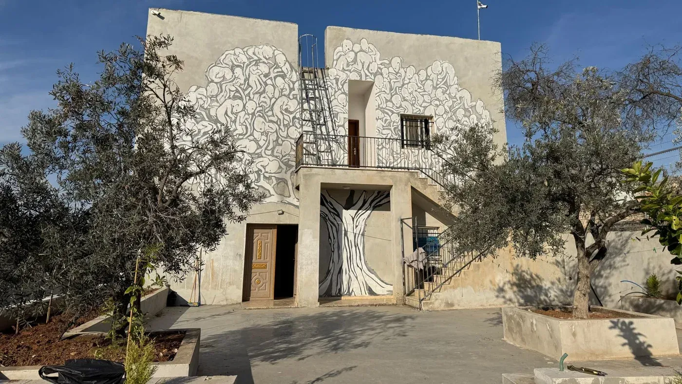 مركز شباب الصمود في التواني، مع جدارية على الجدار، محاط بأشجار الزيتون، يمثل نقطة تجمع للنشاط المجتمعي في مسافر يطا.