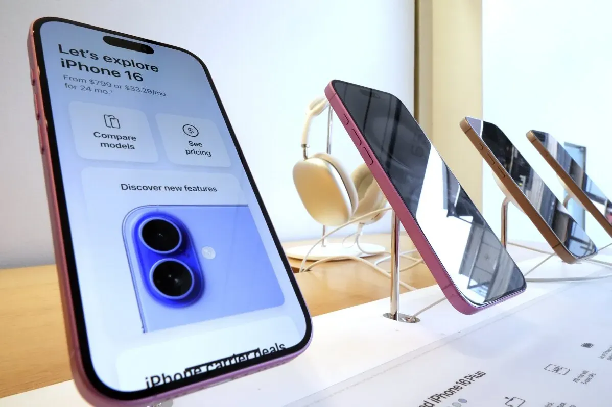 عرض لهواتف iPhone 16 في متجر Apple، مع التركيز على شاشة الهاتف والميزات الجديدة، بينما تظهر نماذج أخرى في الخلفية.