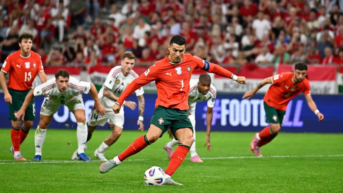 رونالدو، قائد منتخب البرتغال، يسدد ركلة جزاء خلال مباراة في كأس العالم، مع وجود لاعبين من الفريقين في الخلفية.