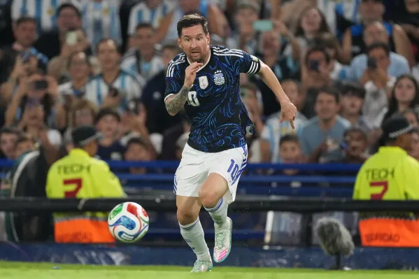 ميسي، لاعب الأرجنتين، يركض في الملعب وسط حماس الجماهير، مع خلفية تظهر مشجعين يرتدون قمصان المنتخب.